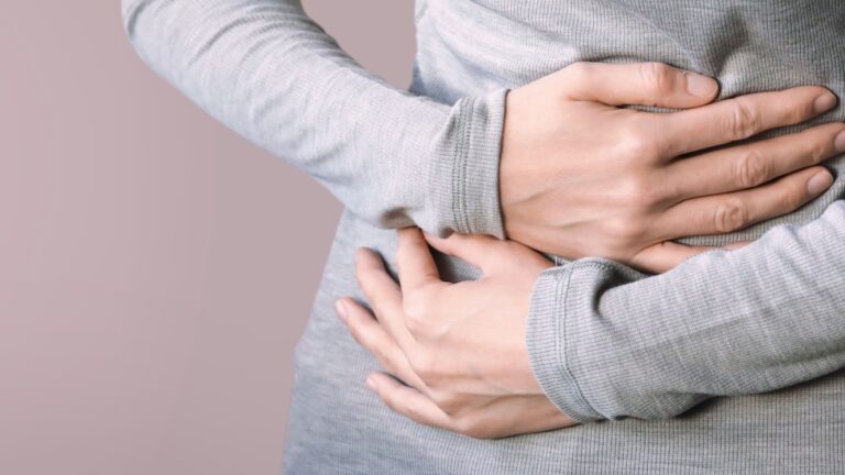 Image of a woman clutching her stomach in pain due to IBS symptoms.